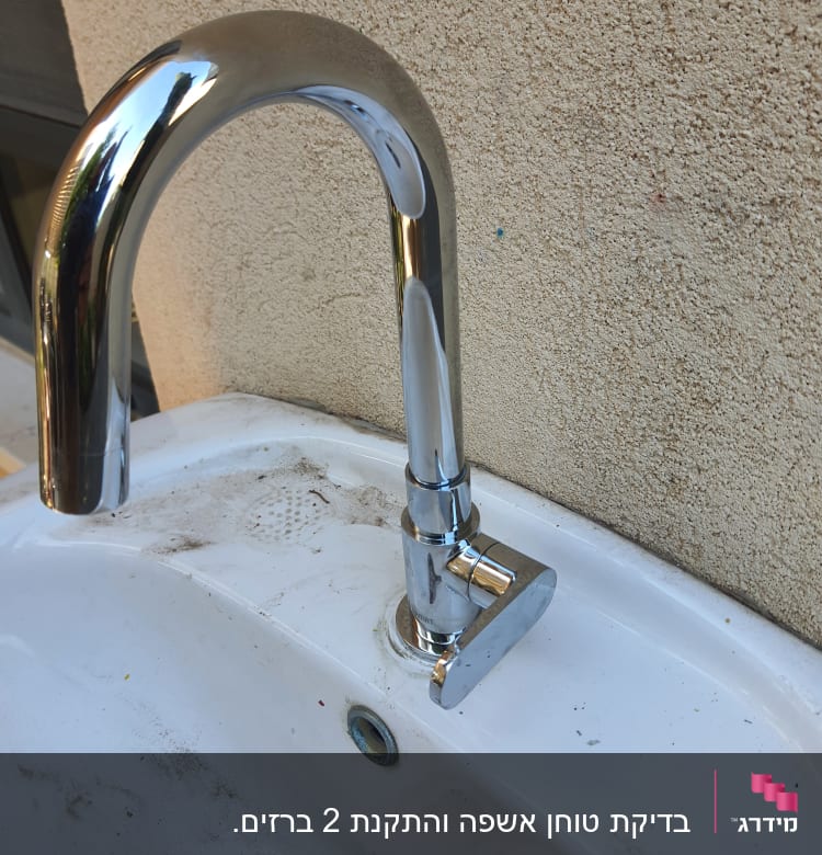 ברז כרום מותקן על כיור לבן עם לכלוך